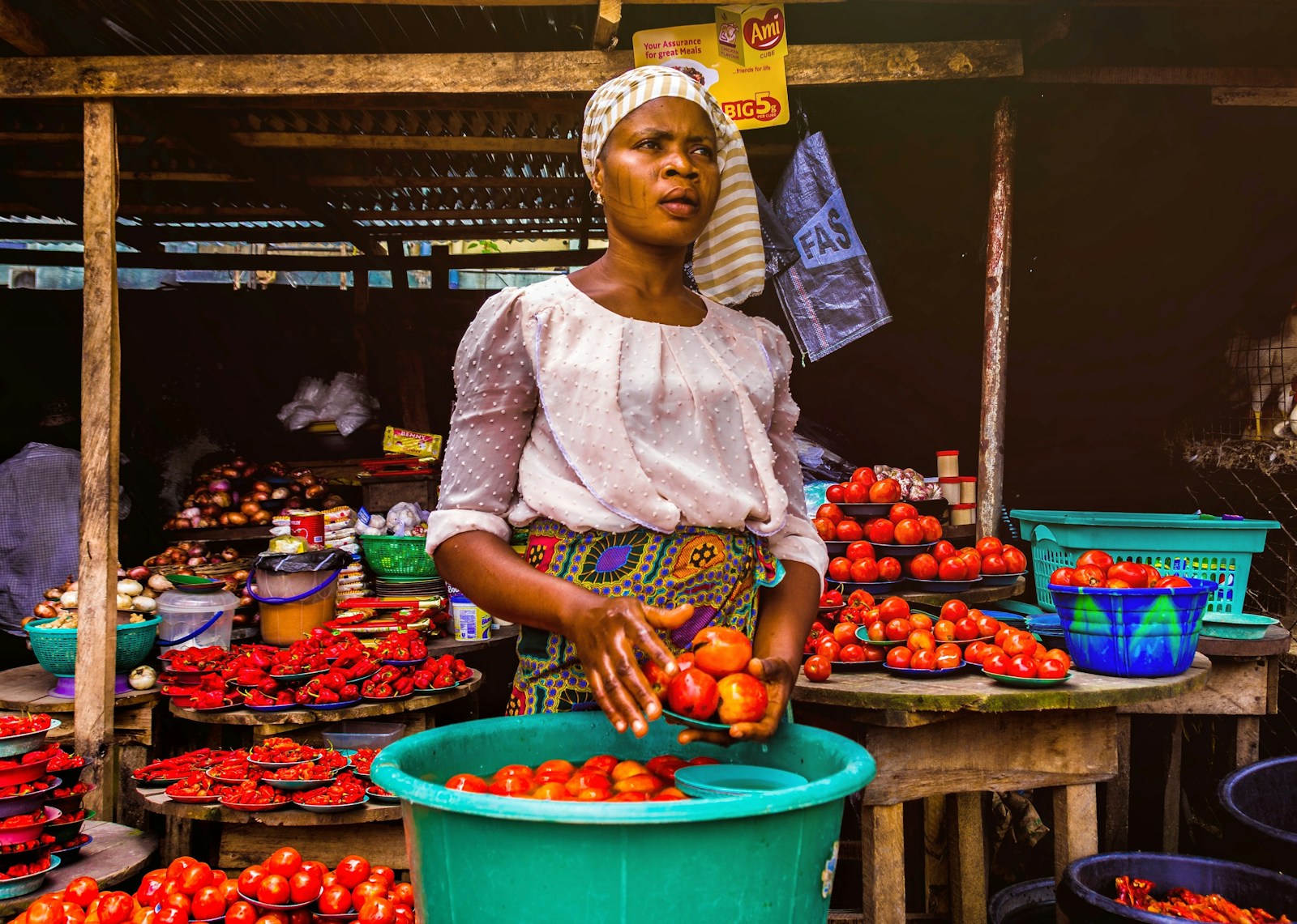 Food Systems Africa: woman holding tomatoes near containers of tomatoes